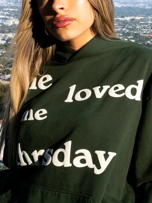 Closeup shot of the woman wearing green hoodie with 'she loved me till thursday' Text
