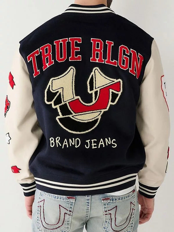 Person wearing a 'True Religion' branded varsity jacket with jeans.
