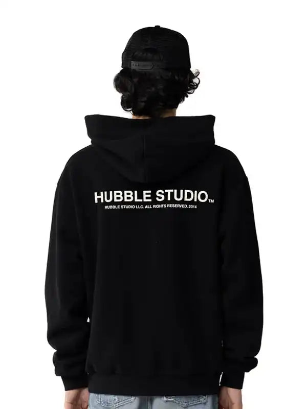 Back view of the black pullover hoodie with the white text 'HUBBLE STUDIO'